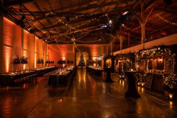 Die festlich dekorierte Halle im Winterquartier mit gedeckten Tischen und Weihnachtsmarktständen für das Buffet.