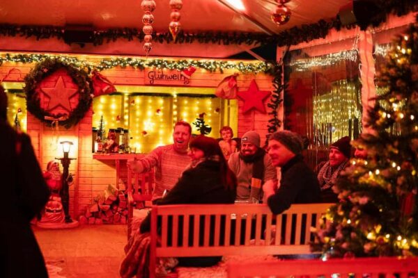 Eine Gruppe sitzt an einem Tisch auf dem Indoor-Weihnachtsmarkt im Dock 10.