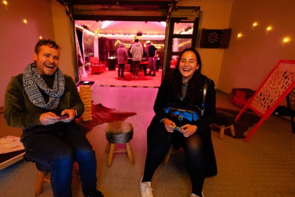 Zwei Personen spielen mit einer Nintendo-Switch. Im Hintergrund steht ein Tischkicker.