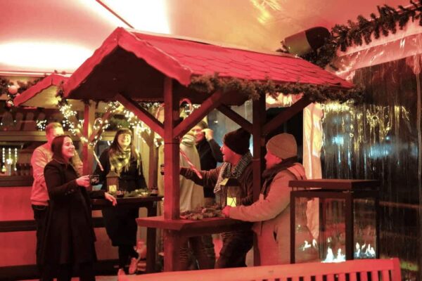 Eine Gruppe steht an einem Indoor-Weihnachtsmarkt im Dock 10.