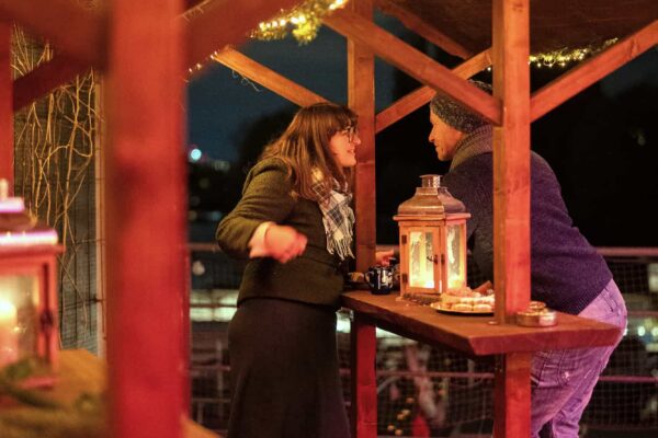 Zwei Personen stehen an einem Tisch auf dem Weihnachtsmarkt im Dock 10.